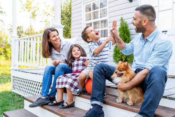 Happy family with two kids sitting in front of american porch